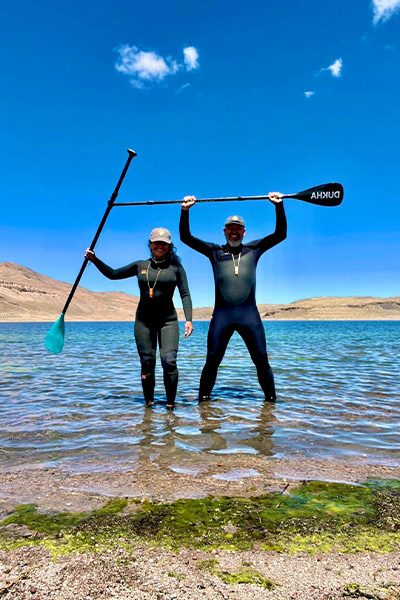 the couple standing in water and holding up oars