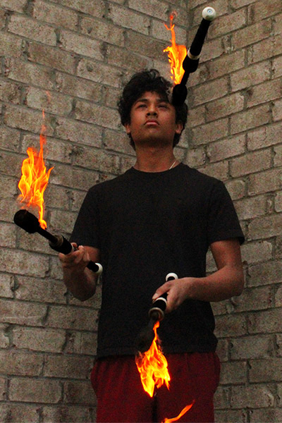 Arnav juggling three flaming torches
