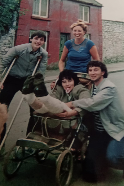 Liam being pushed round in a pram with his legs in plaster