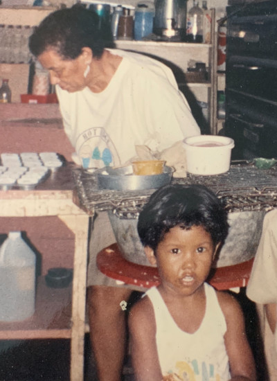 Aileen back in her bakery in Jamaica with a child