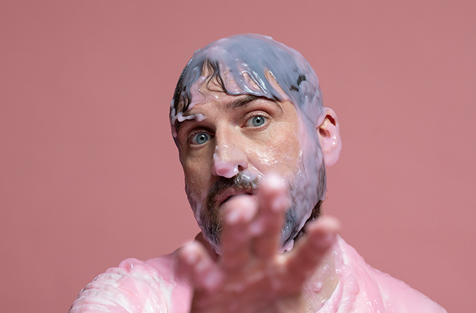 Pictish Trail covered in pink slime reaching out his hand to the camera