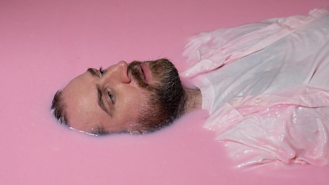 Split image of Pictish Trail having pink slime poured over his head and Pictish Trail lying in a slime bath with the back of his head and his body immersed