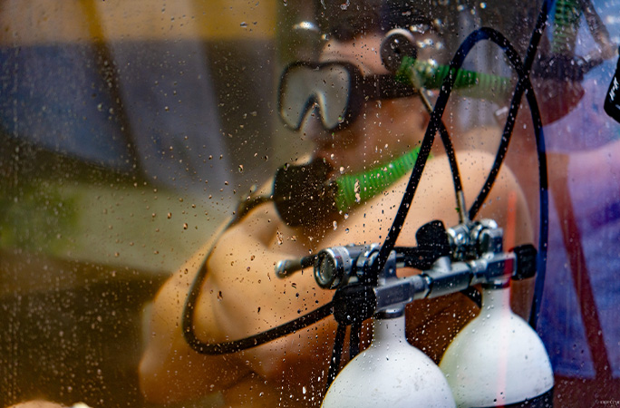 Damian under water with oxygen tanks in the foreground