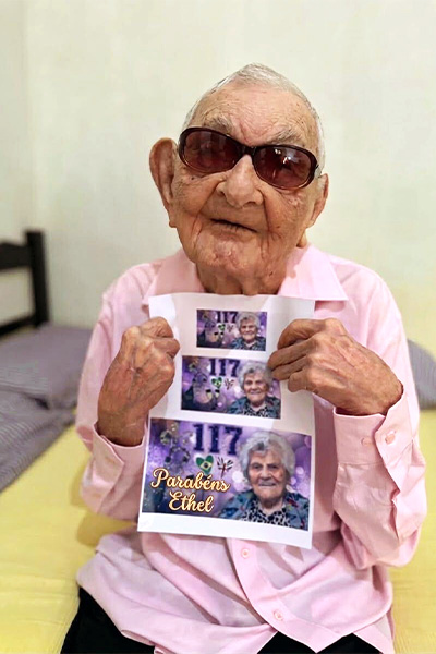Oldest man holding up a birthday picture for Ethel