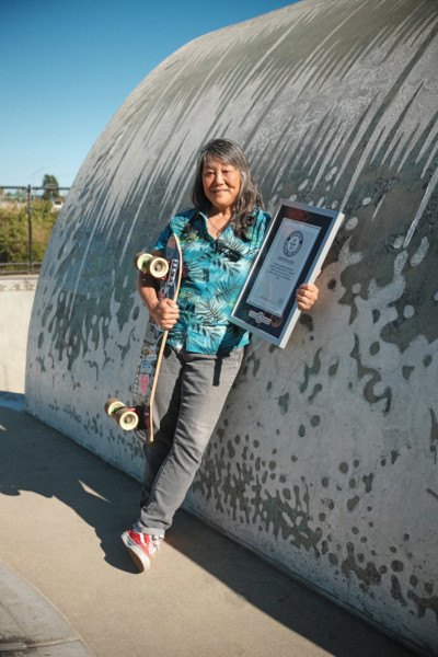 Judi holding her GWR certificate in a skate park