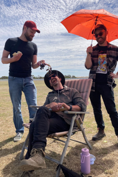 Angus's friends feeding him grapes while he flies the kite