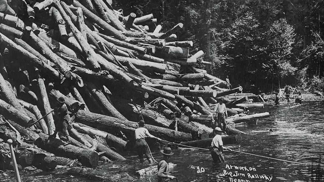 A group of workers attempt to break up a log jam on a river