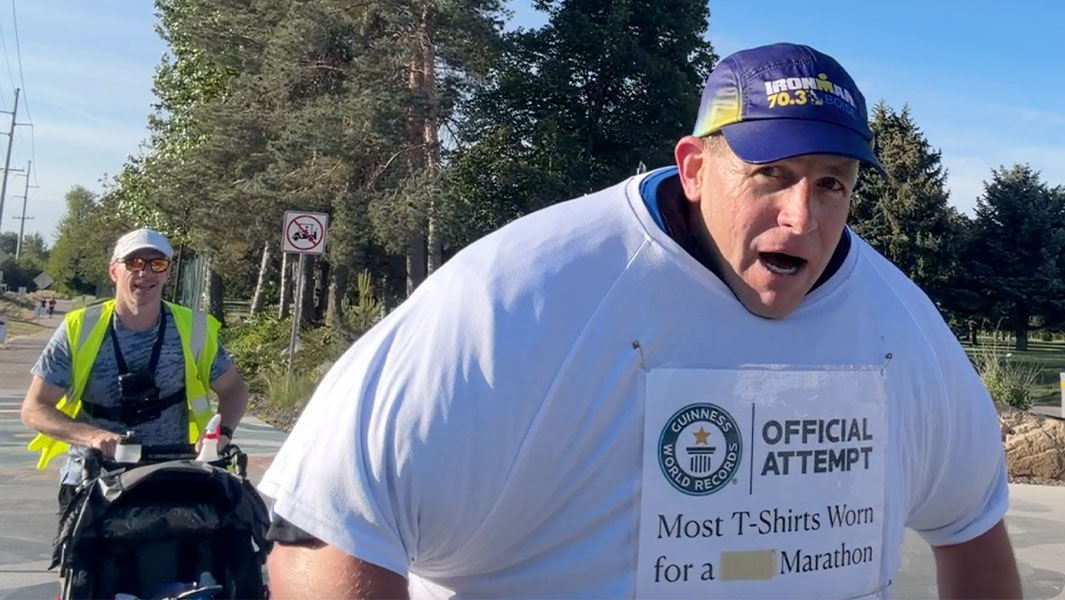 David Rush running a marathon in 125 T-shirts with a man running behind him