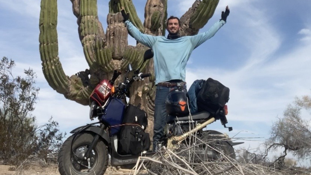Jonathan Roberts and his moped underneath a giant cactus