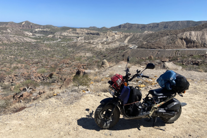 Photo of the moped parked next to a desert scenery
