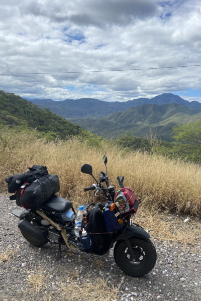 Photo of Jonathan's moped next to a forested mountain