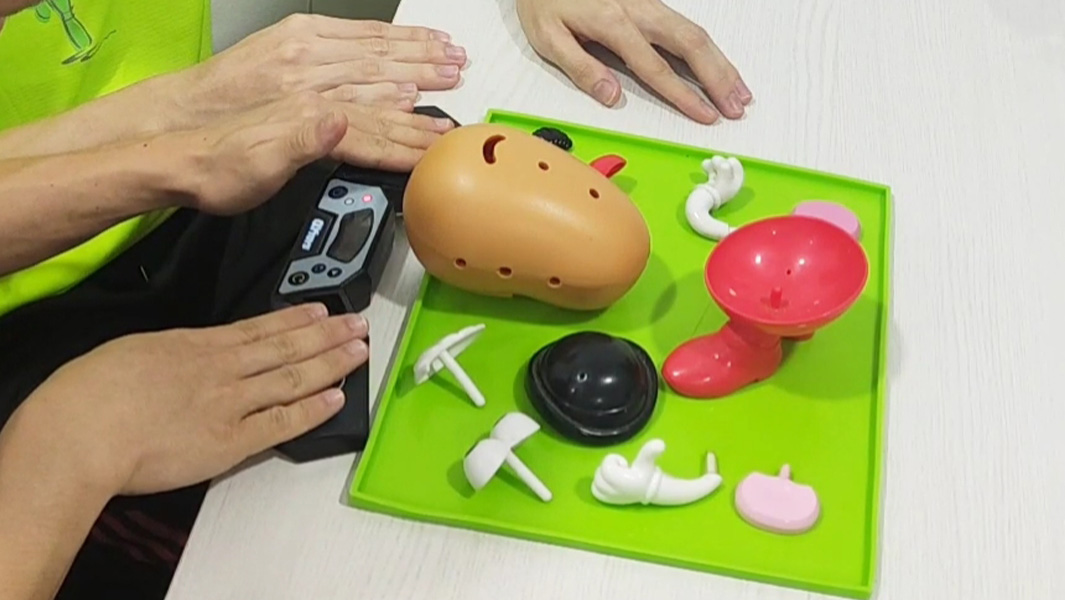 two people working together to build a Mr. Potato Head