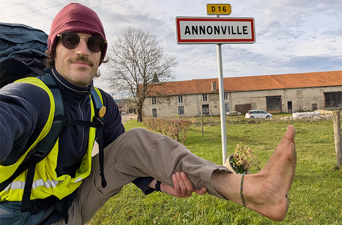Eamonn holding up his foot in front of a road sign