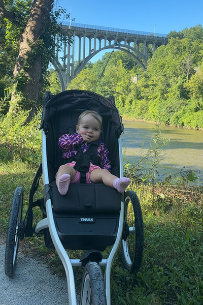 Blake sat in her stroller in front of a bridge and a river