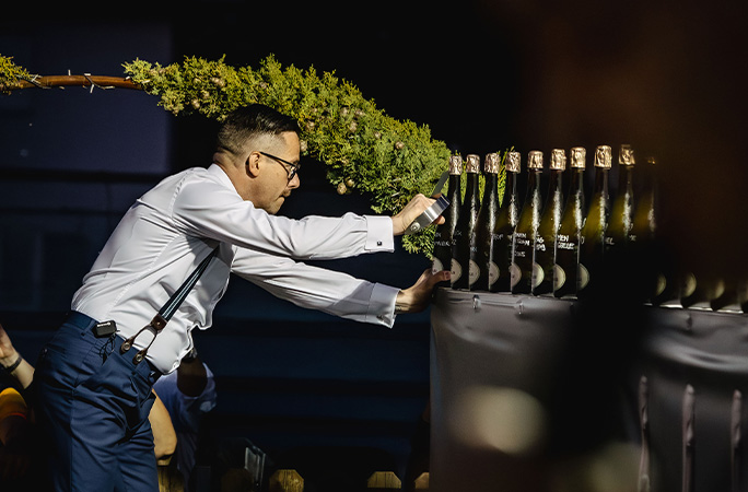 Mirko using a sword to cut the tops off sparkling wine bottles