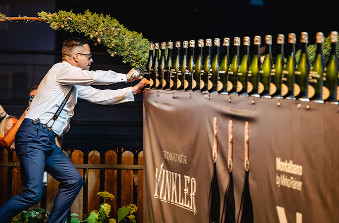 Mirko using a sword to cut the tops off sparkling wine bottles