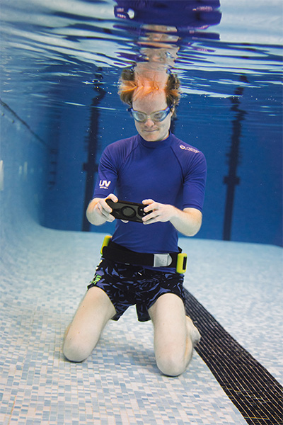 Christian looking at a phone under the water