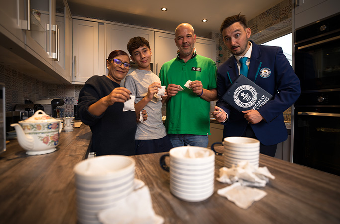 family of three throwing teabags into mugs as GWR Adjudicator Will Munford watches