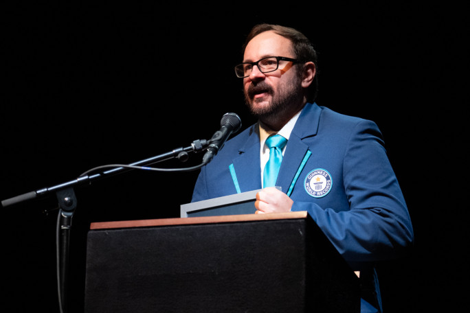 Adjudicator speaking onstage, solo shot