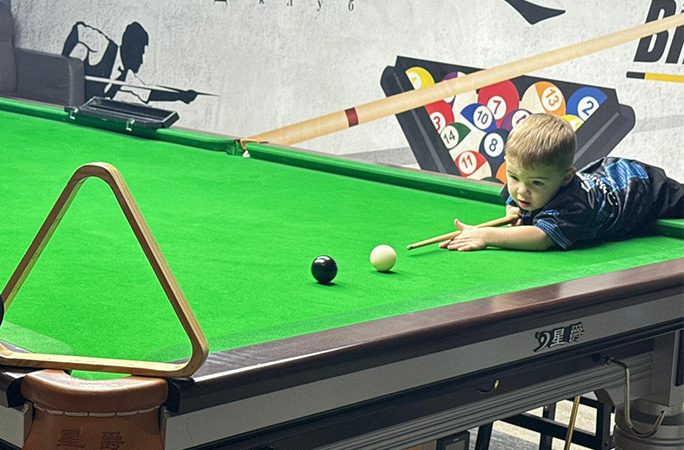 Jude lying on a snooker table making a shot