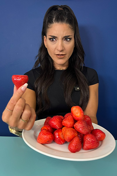 Leah holding up a strawberry with a plate full in front of her
