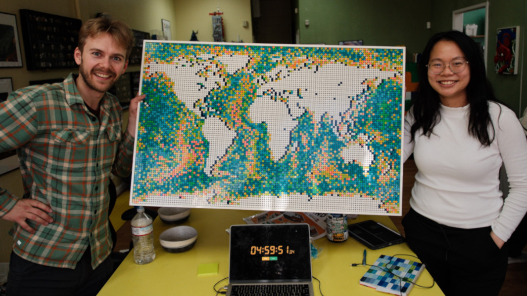 Athena and Sevy smiling with the finished LEGO world map between them