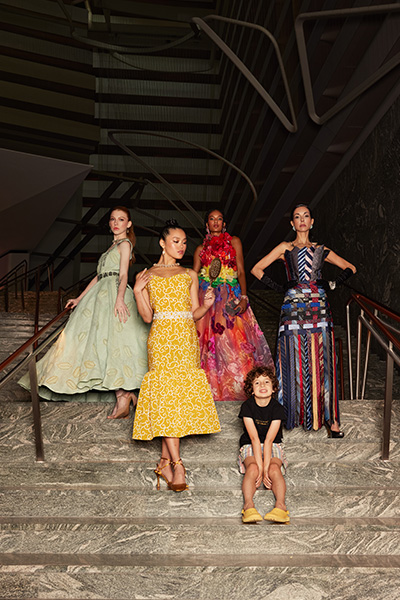 Max sat on some stairs with models wearing his garments