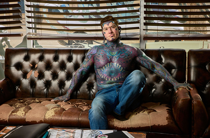 Tattooed man Remy sitting on a sofa