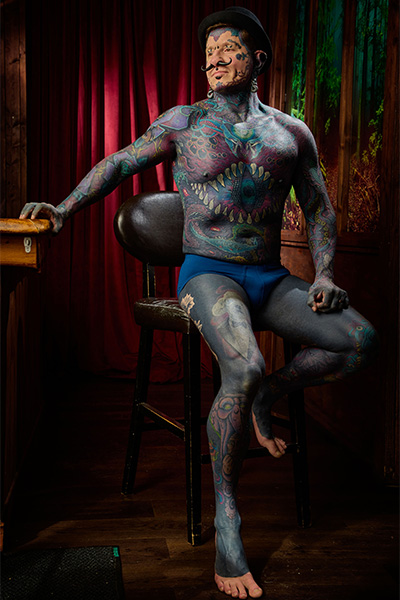 Tattooed man Remy sitting on a stool