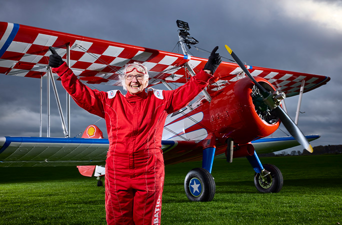 Betty in a red jumpsuit standing in front of a plane