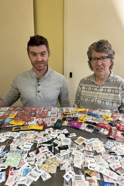 Linda and a man smiling in front of all of her packets