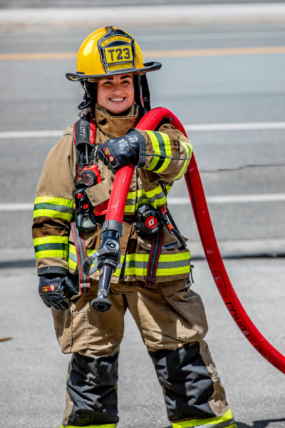 Autumn in her firefighter uniform, holding a hose