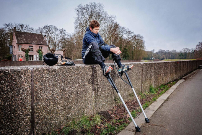 Jonathan sitting on the canal bank and strapping on his stilts
