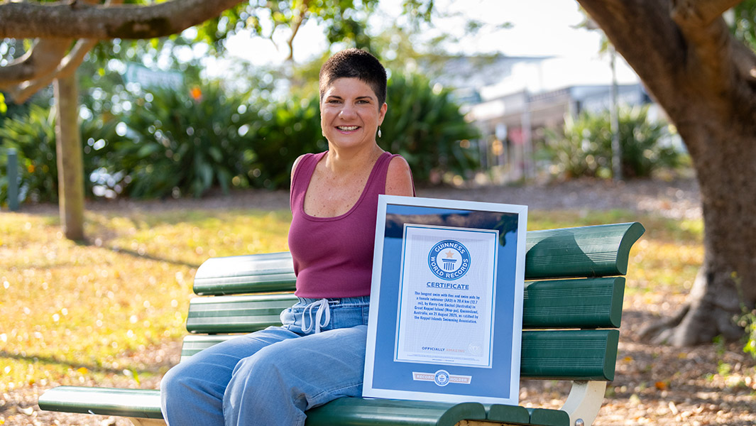 wingless-warrior-kerry-lee-gockel-on-bench-with-her-gwr-certificate-and-swimming-off-great-keppel-island