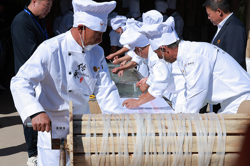 craftsmen-rolling-potato-noodle-on-wooden-wheel