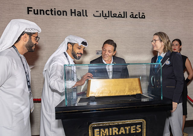 A group of people standing around the largest bar of gold with an adjudicator