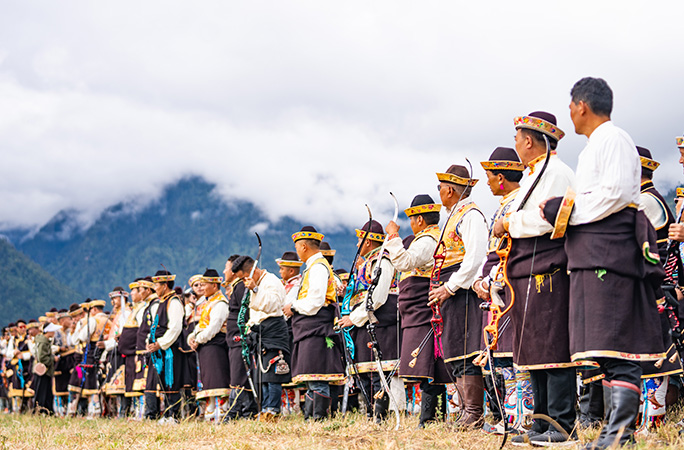 a row of people wearing traditional wear take part in the largest whistle archery