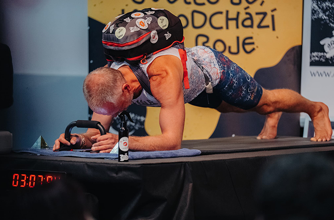 man performs an abdominal plank with a 40lb backpack with stickers