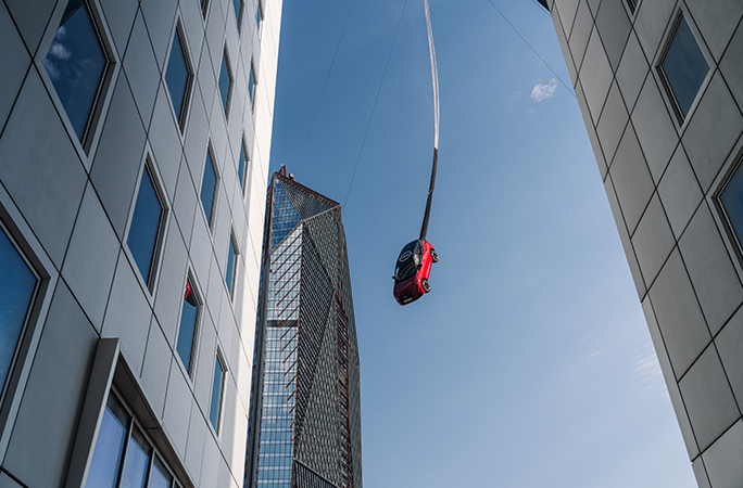 a-red-car-suspends-in-the-air-via-bungee-rope
