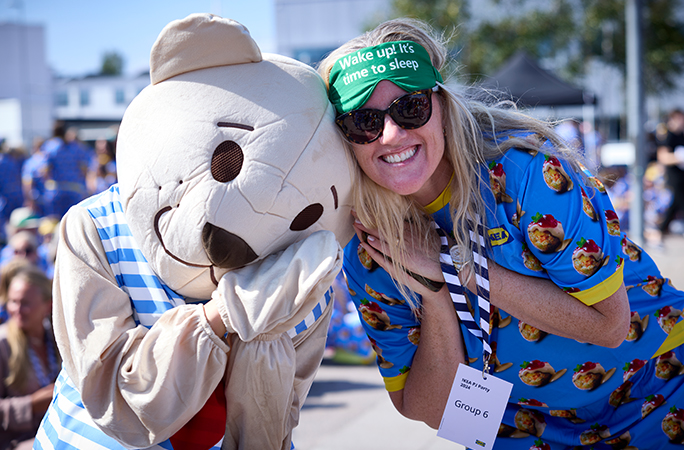 a woman poses with a white bear mascot wearing two piece pajamas