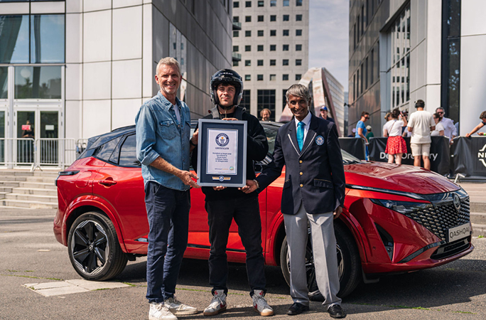 three-men-stand-in-front-of-a-red-nissan-holding-a-guinness-world-records-certificate