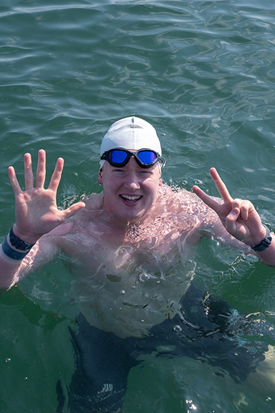 a man in a sea of water makes a peace sign with his fingers
