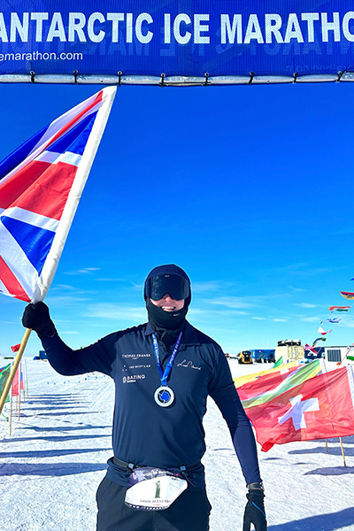 a man wearing a heavy coat and snow goggles holding a united kingdom flag
