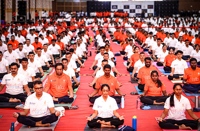 rows of participants perform yoga poses