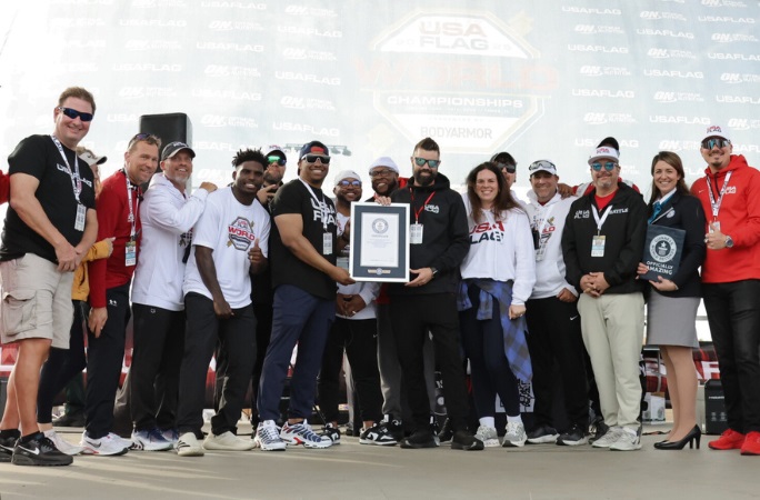 Group of people standing next to the Guinness World Records certificate for largest flag football
