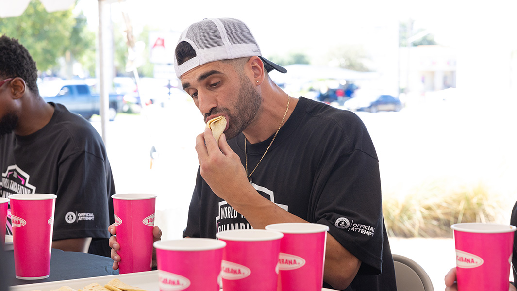 a man wearing a black t shirt bites into a taco