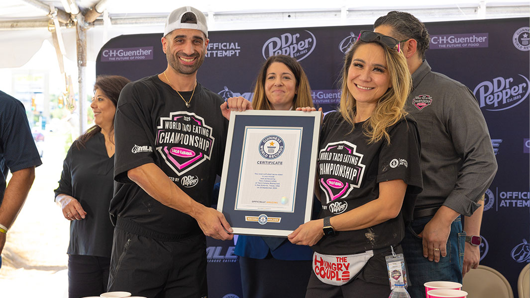 a woman and man dressed in black smile holding a guinness world records certificate
