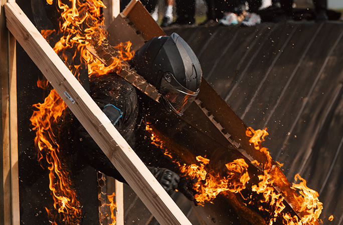 a man dressed in black runs through a door on fire