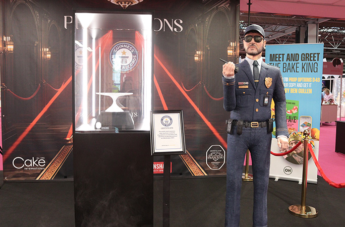 a crystal cake stand is presented alongside a security guard also made out of cake