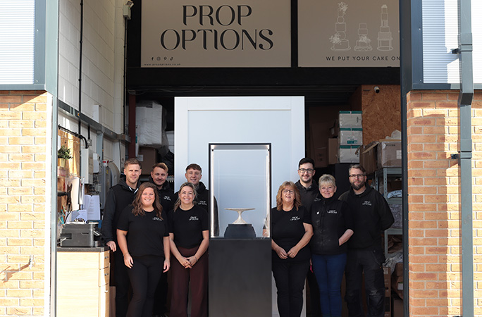 prop options team stands next to the most expensive cake stand with smiles on their faces